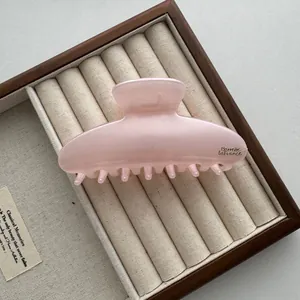 Close-up van een grote roze haarklem van 13 cm in een klassieke sieradenhouder tray