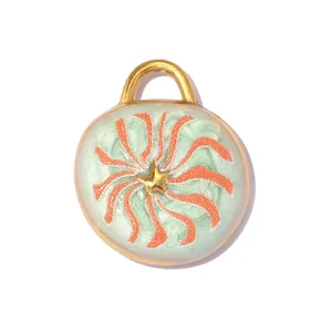 Macro view of circular stainless steel pendant with green enamel and gold star motif