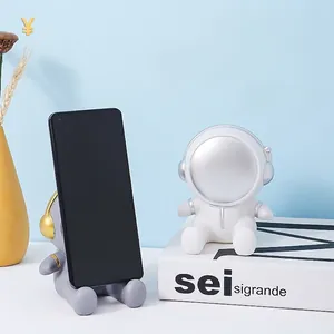 Creative astronaut figurine phone holder for desk with minimalist space theme design