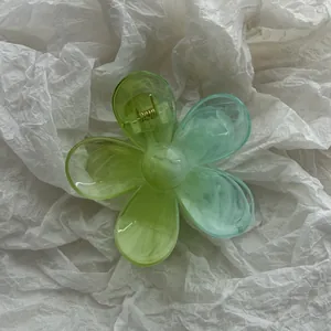 Vista dettagliata di un fermaglio per capelli a forma di fiore plumeria con sfumatura verde.