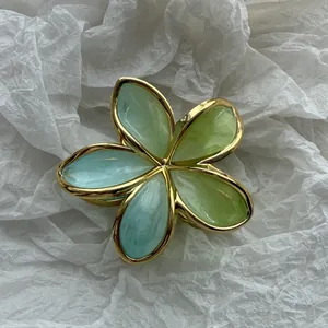 Dettaglio macro di una pinza per capelli a fiore di frangipane verde con eleganti bordi d'oro