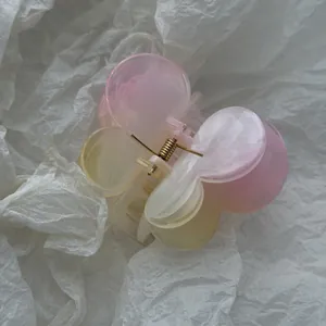 Close-up of marbled pink and yellow frangipani floral hair claw clip texture detail