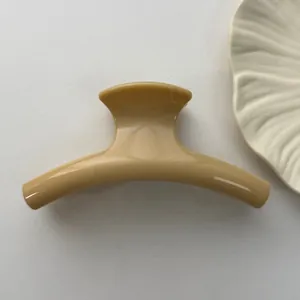 Close-up view of a high-quality glossy beige minimalist hair claw clip for elegant hairstyles
