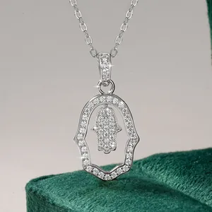 Detailed close-up of sparkling Hamsa hand pendant necklace on luxury green velvet box