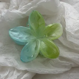Detailopname van doorschijnende groen en blauw gradiënt frangipani haarklemmetje