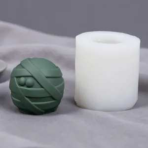Detailed view of the mummy ball silicone mold next to the finished green candle.