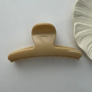 Detailed view of the smooth finish and curved design of this beige hair claw clip