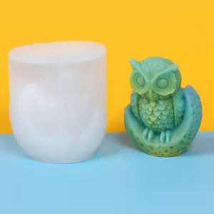 Detailed view of a 3D owl on moon silicone mold beside a finished green candle