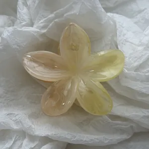 Gedetailleerde weergave van een plumeria haarklem met elegant gemarmerd effect.