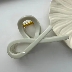 Close-up of minimalist light green PC hair claw clip with golden spring mechanism