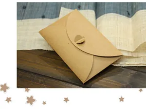 Detail of retro kraft paper envelope featuring a heart-shaped closure on wooden table