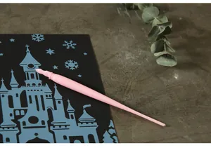 Close-up of a pink plastic scratch art pen on a castle design scratchboard sheet