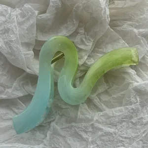 Dettaglio di una pinza per capelli ondulata con sfumatura di colore verde e azzurro.