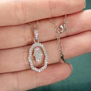Close-up detail of silver Hamsa Hand pendant with sparkling stones on green background