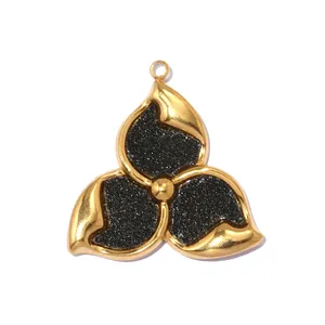 Macro view of a three-petal flower pendant featuring black glitter inlay and polished gold finish
