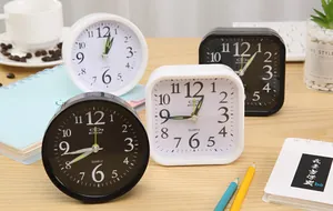 Group of four minimalist black and white analog desk alarm clocks on a wooden table setup
