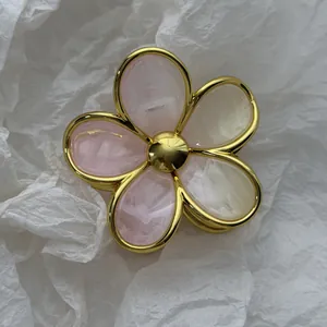 Detail shot of an elegant gold-framed marbled resin flower hair claw clip on white background