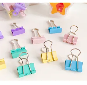 Close-up macro view of colorful macaron binder clips scattered on a white desk surface