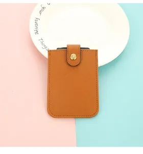 Detail view of brown PU leather card holder with button closure on pink and blue background