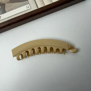 Gedetailleerd overzicht van een minimalistische beige banaan haarklem met stevige grip tanden