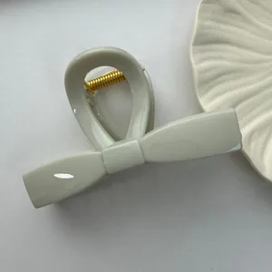 Detailed close-up view of a minimalist light grey bow-shaped large plastic hair claw clip