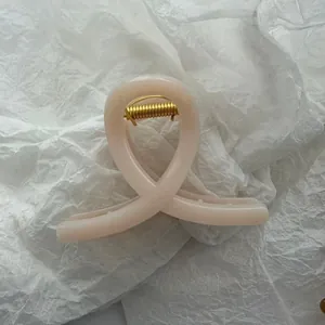 Macro view of a translucent peach jelly hair claw clip placed on white textured tissue paper.