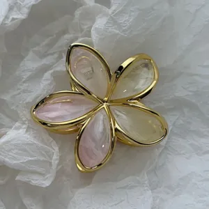 Macro view of a small marbled frangipani hair claw clip with elegant golden metal edges.