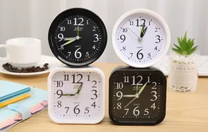 Close-up of minimalist black and white quartz alarm clocks on a modern wooden desk