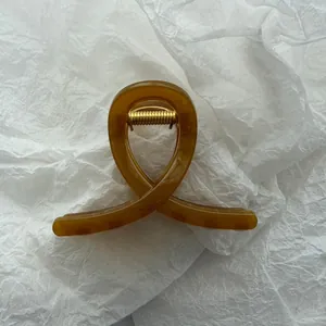 Detail view of a translucent amber jelly hair claw clip on white textured background