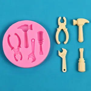 Détail du moule en silicone rose avec des fondants en forme d'outils pour gâteaux