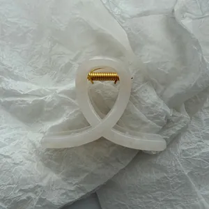 Detailed macro view of an elegant cream white jelly hair claw clip with durable gold spring