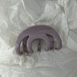 Primo piano di un fermaglio per capelli viola fatto a mano su sfondo di carta bianca stropicciata.