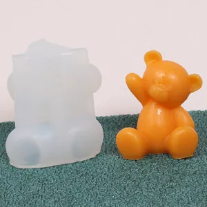 Detail of a silicone bear mold alongside a finished orange wax bear figurine