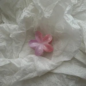 Detailopname van een roze kleurverloop bloem haarklem op wit kreukelig papier achtergrond