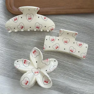 Close-up of hair claw clips set featuring cute heart and cherry patterns on white base