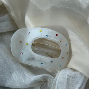 Detailed macro view of cream white acetate hair claw clip decorated with colorful rhinestones