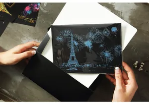 Hand holding an Eiffel Tower city night view scratch art postcard with a black envelope