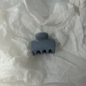 Vista dettagliata di una molletta per capelli minimalista blu-grigio su carta bianca