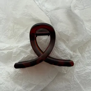 Macro detail of a vintage tortoiseshell patterned hair claw clip on white textured paper