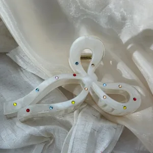 Detail of cream marbled bow hair claw clip with multi-color rhinestones