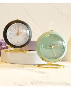 Detail view of minimalist round desktop clocks in black and green with gold stands