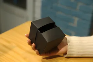 Vista detallada de una mano sosteniendo la caja de regalo sorpresa negra mate hecha a mano.