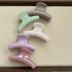 Detail view of five assorted pastel-colored jelly resin mini hair claw clips on a beige tray