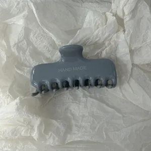 Vista dettagliata di una pinza per capelli grigio blu con scritta HAND MADE