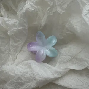 Detail van een plumeria haarklem met een zacht kleurverloop in paars en blauwe tinten