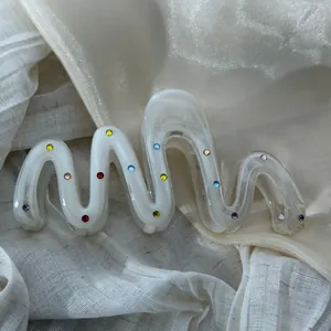 Detailed macro view of a wavy white hair claw clip accented with vibrant colorful rhinestones