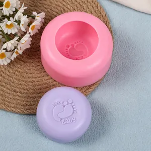 Close-up of a pink round silicone mold and purple soap with a baby footprint design