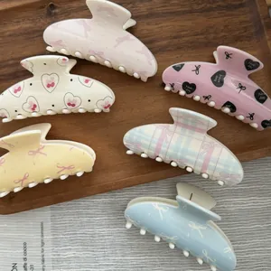 Detailed view of macaron colored Valentine's Day hair claw clips with heart and bow patterns
