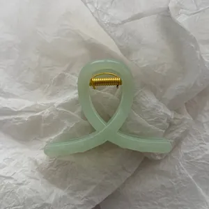 Detailed view of a mint green jelly hair claw clip with an elegant cross-loop design