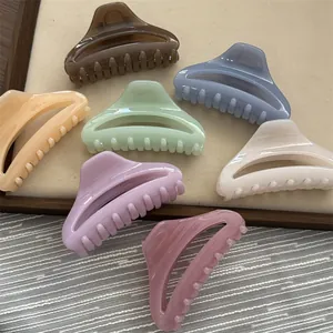 Variety of colorful glossy hair claw clips displayed on a tray for hair styling.